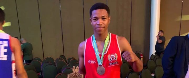 Thauan da Silva com uma medalha no peito e fazendo um gesto de soco com a mão